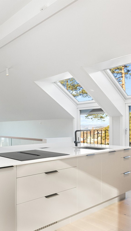 Kjøkken under skråtak med store, flotte takvinduer og veggvinduer - MSH Bygg
