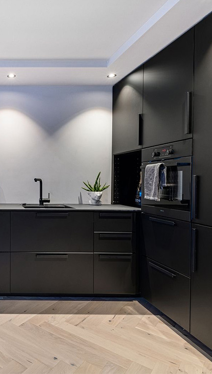 Utsnitt av sort, stilig kjøkkeninnredning med innebygget stekeovn i sort